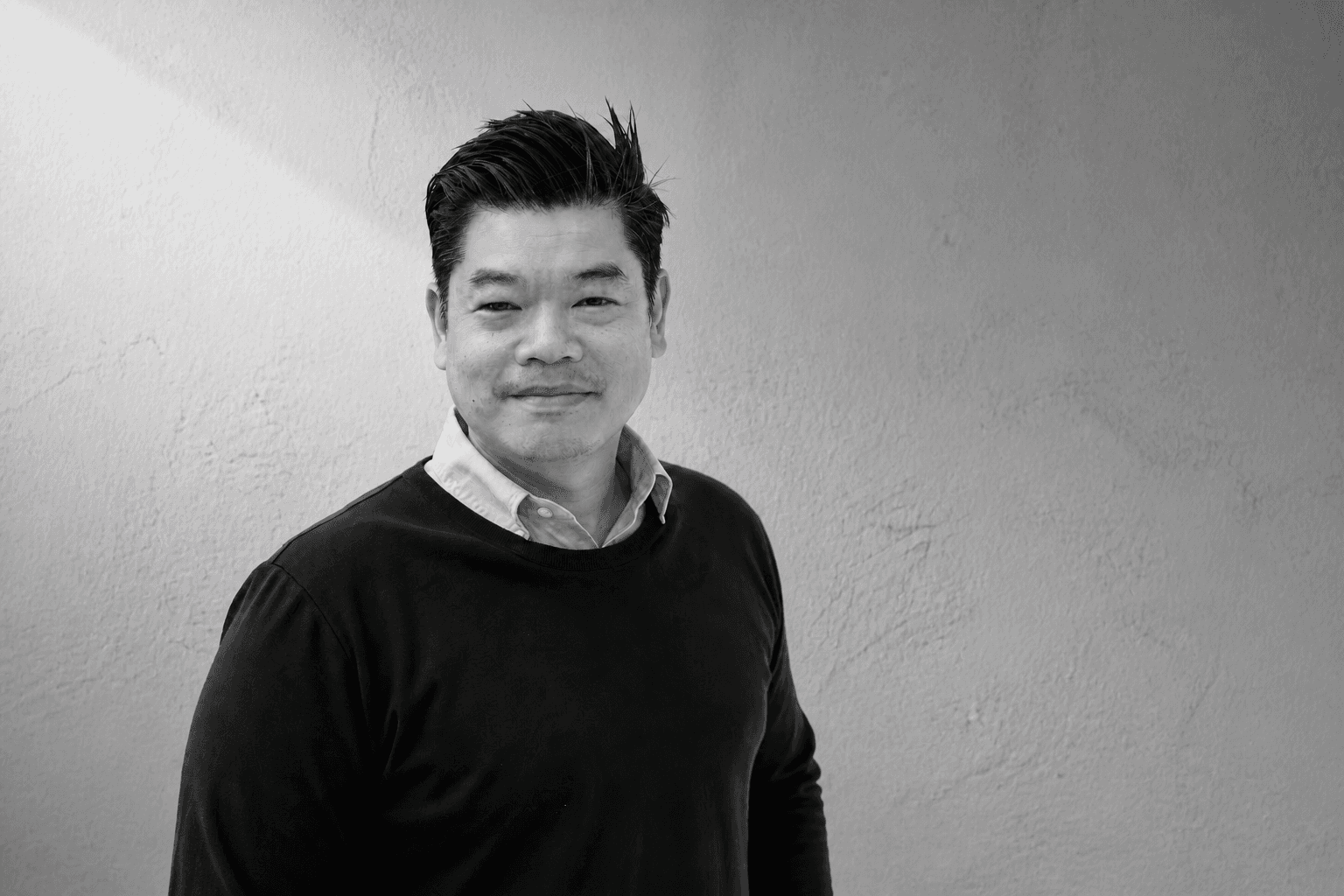 Founder Tom Jakkapat standing against a simple textured wall